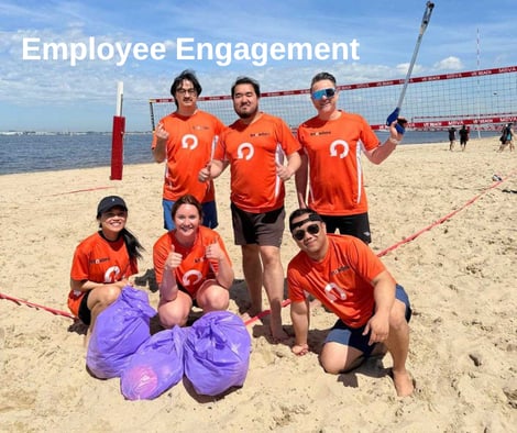 Employees in KnowBe4 Orange Shirts posing by collected trash on the beach